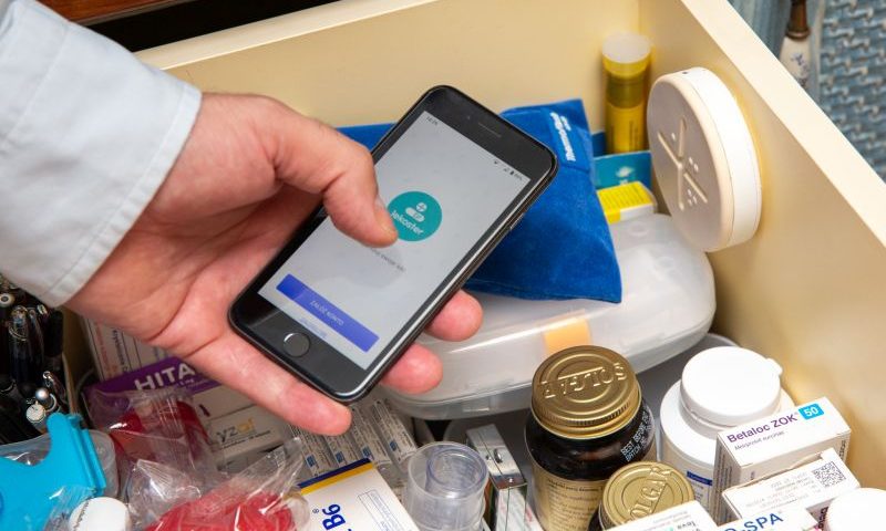 smartfon z otwartą aplikacją lekoster tryzmany w ręku nad szufladą wypełnioną lekami