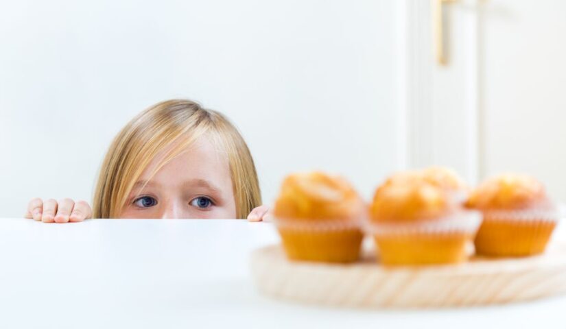 dziecko spogląda na postawione na stole słodkie ciastka