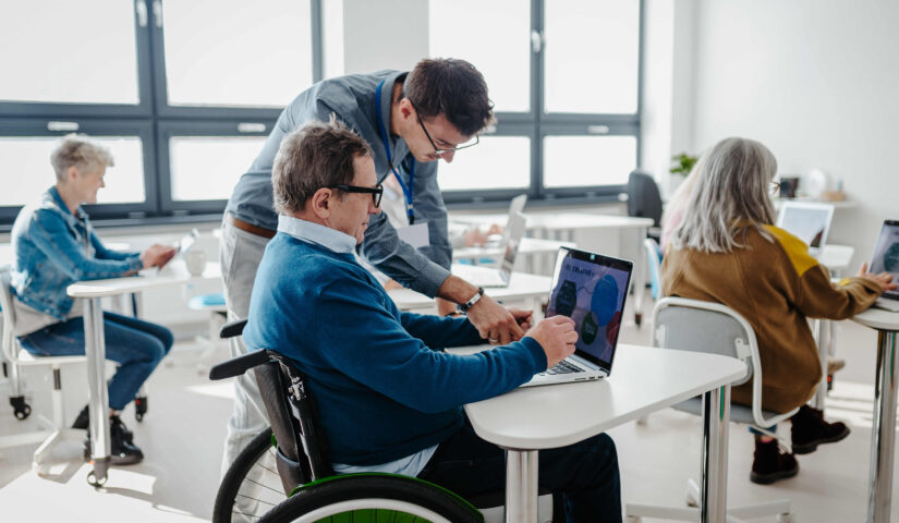 Nauczyciel wyjaśnia starszym uczniom, jak pracować z laptopem i internetem