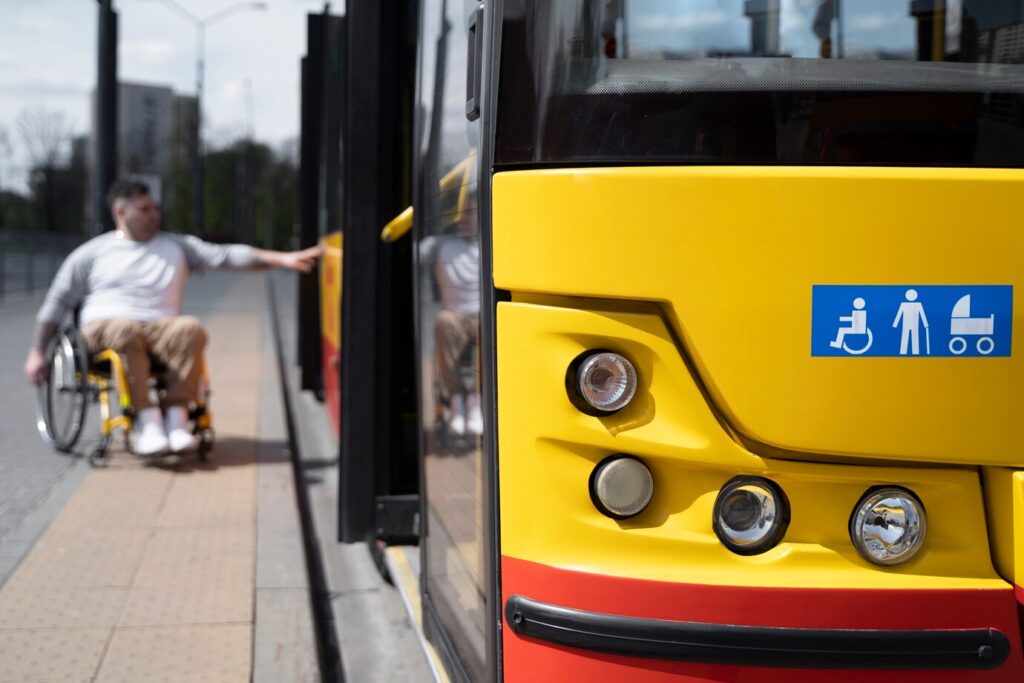 Mężczyzna na wózku wsiada do autobusu niskopodłogowego, fot. Freepik